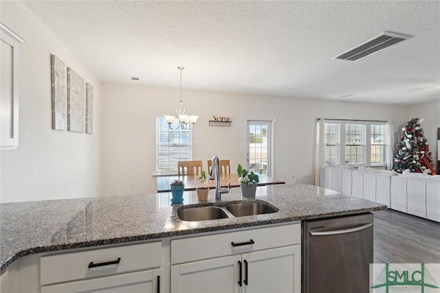 kitchen with white cabinetry, sink, dishwasher, an inviting chandelier, and dark stone counters