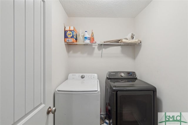 clothes washing area featuring a textured ceiling and washer and clothes dryer