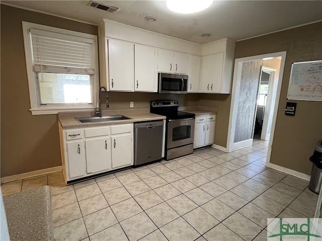 kitchen with white cabinetry, appliances with stainless steel finishes, sink, and light tile patterned floors