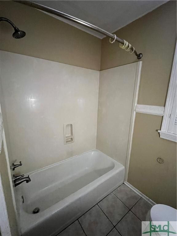 bathroom with tile patterned flooring, bathing tub / shower combination, and toilet