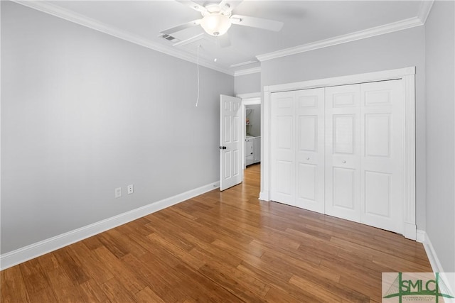 unfurnished bedroom with ceiling fan, ornamental molding, a closet, and wood-type flooring