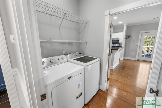 laundry area with hardwood / wood-style flooring, washer and dryer, and crown molding