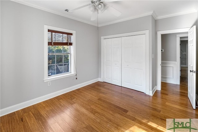 unfurnished bedroom featuring wood-type flooring, ceiling fan, crown molding, and a closet