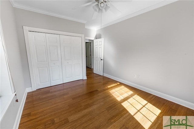 unfurnished bedroom with dark wood-type flooring, ceiling fan, a closet, and ornamental molding