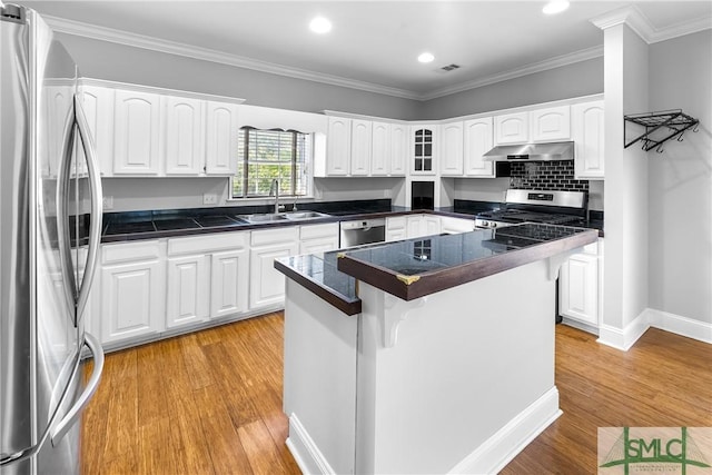 kitchen featuring appliances with stainless steel finishes, white cabinets, a center island, and sink