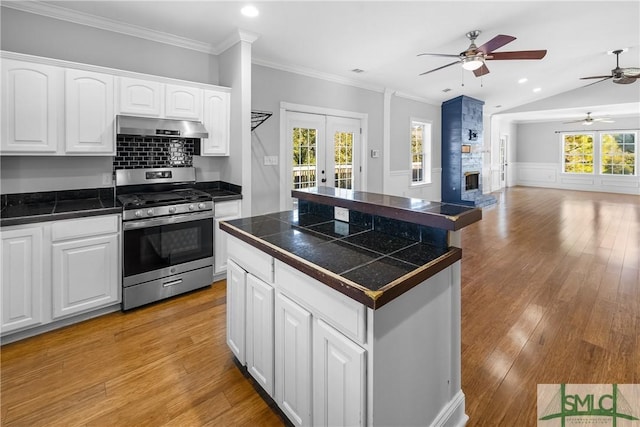 kitchen featuring stainless steel range with gas stovetop, a center island, french doors, white cabinets, and lofted ceiling