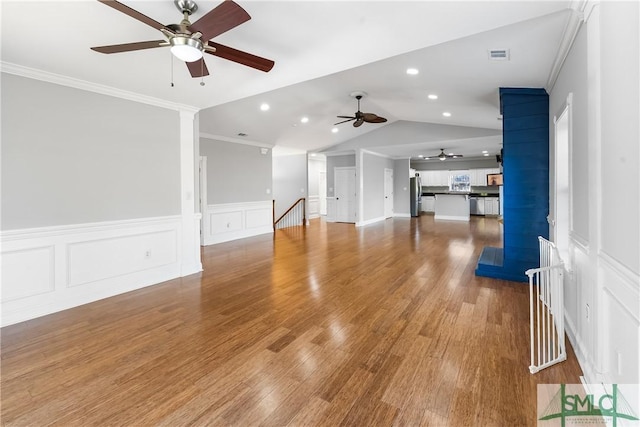 unfurnished living room with ceiling fan, hardwood / wood-style floors, ornamental molding, and vaulted ceiling