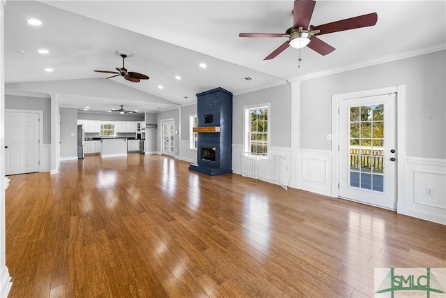 unfurnished living room with wood-type flooring, a wealth of natural light, a large fireplace, and vaulted ceiling