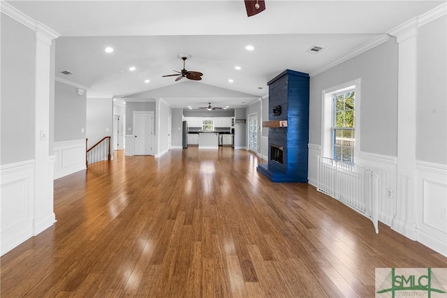 unfurnished living room featuring a fireplace, ceiling fan, vaulted ceiling, and ornamental molding