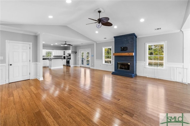 unfurnished living room featuring a large fireplace, light hardwood / wood-style flooring, ornamental molding, and lofted ceiling