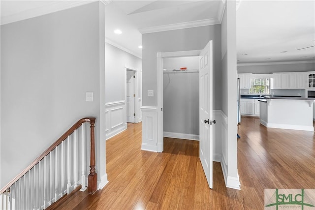 corridor with light hardwood / wood-style floors and crown molding