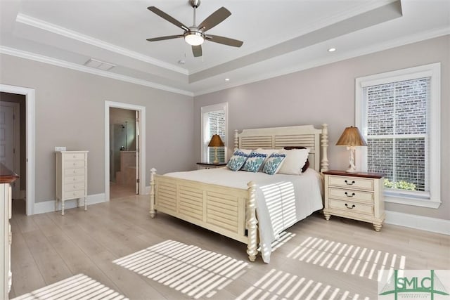 bedroom with a raised ceiling, ceiling fan, ensuite bathroom, and ornamental molding