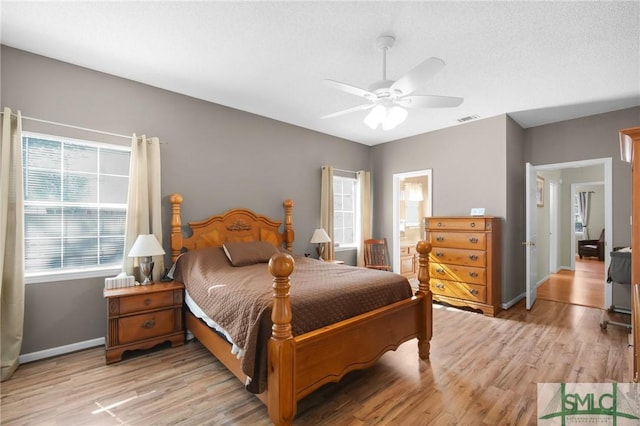 bedroom with ceiling fan, light hardwood / wood-style flooring, ensuite bathroom, and a textured ceiling