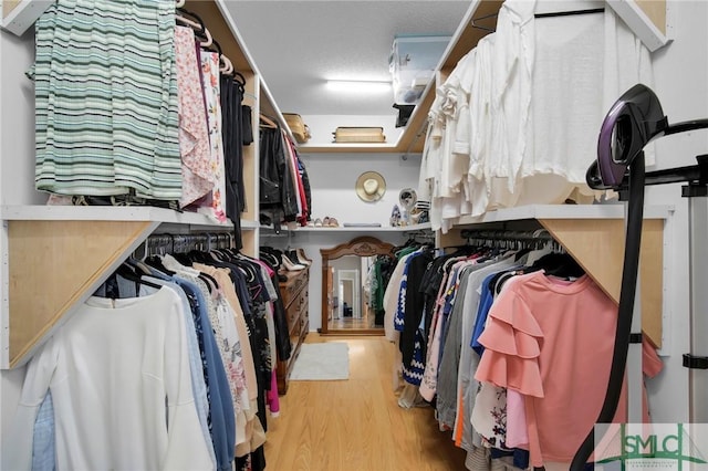 walk in closet with light hardwood / wood-style floors