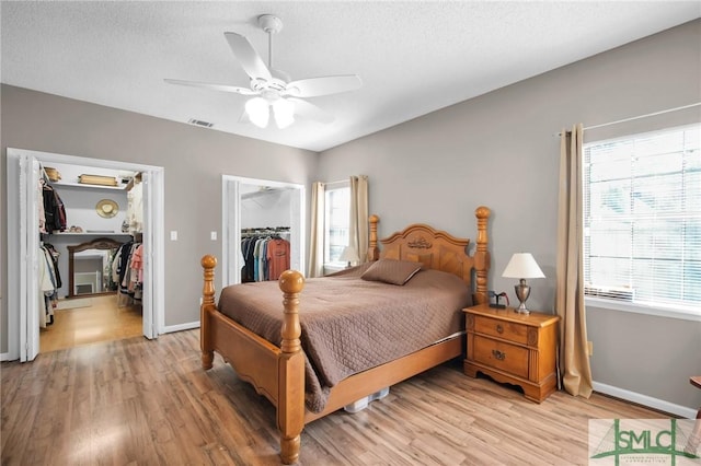 bedroom featuring ceiling fan, light wood-type flooring, a spacious closet, multiple windows, and a closet