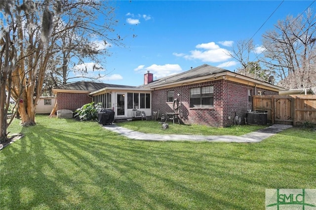 rear view of house featuring a lawn and a sunroom