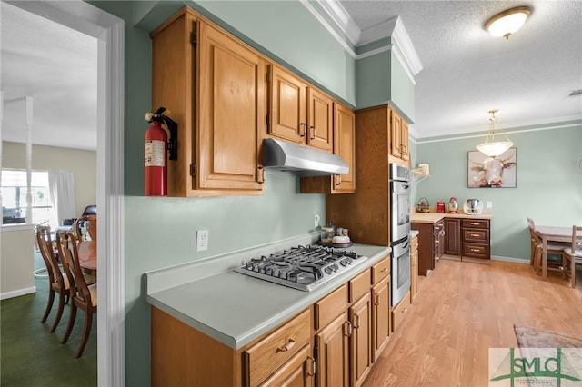 kitchen with hanging light fixtures, ornamental molding, a textured ceiling, light hardwood / wood-style floors, and stainless steel appliances