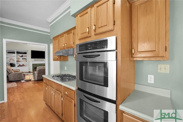 kitchen featuring light wood-type flooring, ornamental molding, stainless steel appliances, light brown cabinets, and built in features