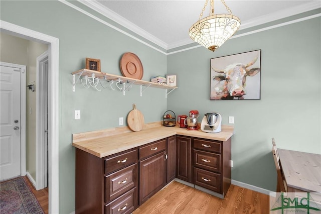 kitchen with dark brown cabinetry, crown molding, light hardwood / wood-style flooring, and decorative light fixtures