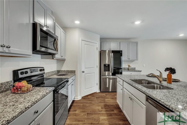 kitchen featuring dark hardwood / wood-style flooring, light stone countertops, sink, and appliances with stainless steel finishes