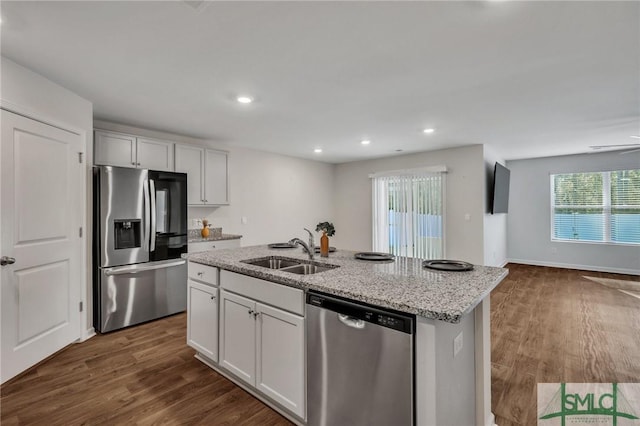 kitchen featuring light stone countertops, stainless steel appliances, sink, white cabinets, and an island with sink