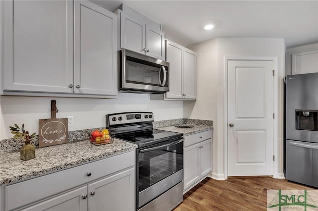 kitchen featuring light stone countertops, stainless steel appliances, white cabinets, and dark hardwood / wood-style floors