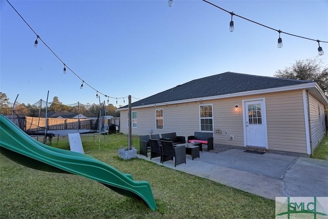 back of house featuring outdoor lounge area, a patio area, a trampoline, a playground, and a lawn