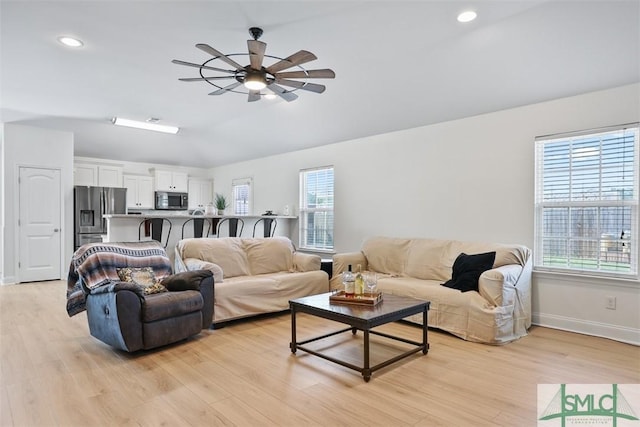 living room featuring ceiling fan, light wood-type flooring, and a wealth of natural light