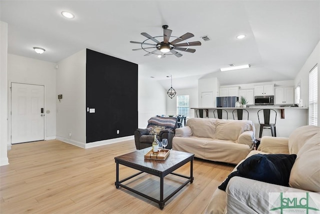 living room featuring ceiling fan, vaulted ceiling, and light hardwood / wood-style flooring