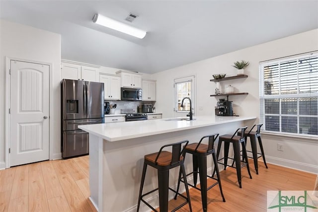 kitchen with white cabinetry, sink, a kitchen breakfast bar, kitchen peninsula, and appliances with stainless steel finishes