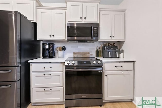 kitchen with white cabinetry, light hardwood / wood-style flooring, appliances with stainless steel finishes, and tasteful backsplash