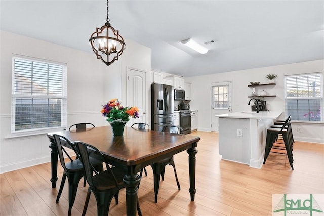 dining room with sink, light hardwood / wood-style floors, and a notable chandelier