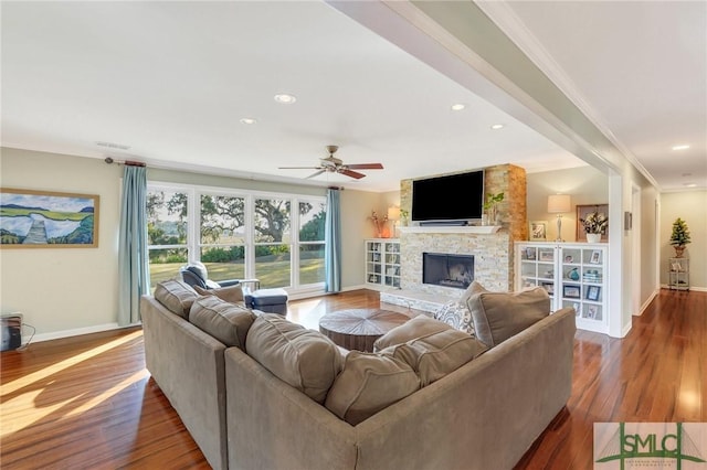 living room featuring hardwood / wood-style floors, ceiling fan, ornamental molding, and a fireplace