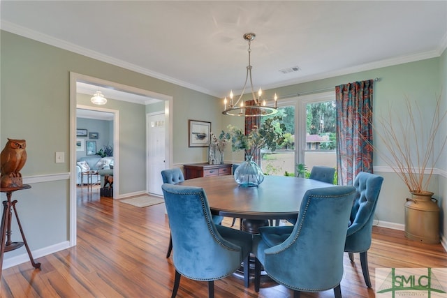 dining room with a notable chandelier, light hardwood / wood-style floors, and ornamental molding