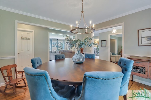 dining space featuring crown molding, light wood-type flooring, and a notable chandelier