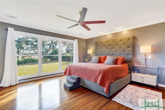 bedroom with baseboard heating, ceiling fan, and hardwood / wood-style floors