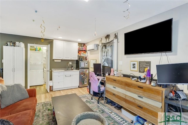 living room with an AC wall unit, sink, stacked washer and dryer, and light wood-type flooring