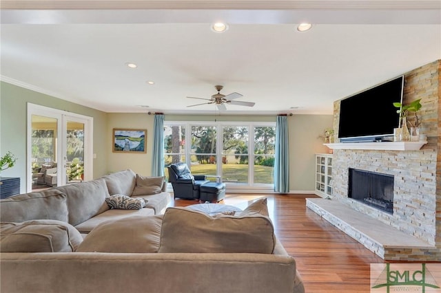 living room featuring french doors, crown molding, hardwood / wood-style flooring, ceiling fan, and a fireplace