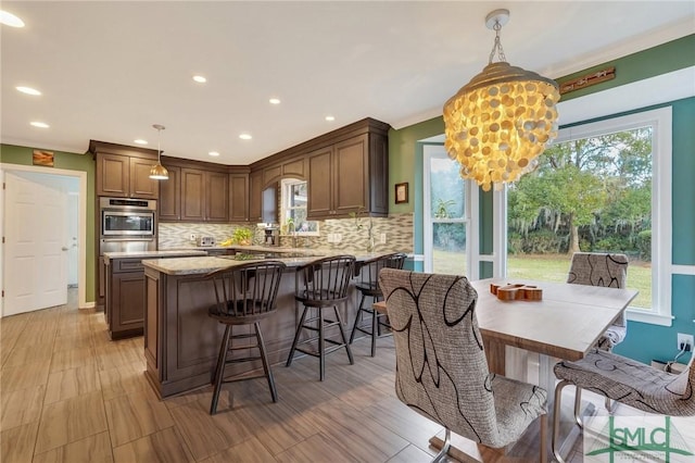 kitchen with backsplash, light stone countertops, a healthy amount of sunlight, and decorative light fixtures