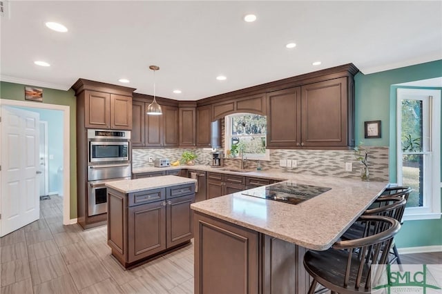 kitchen with pendant lighting, sink, black electric cooktop, kitchen peninsula, and a breakfast bar area