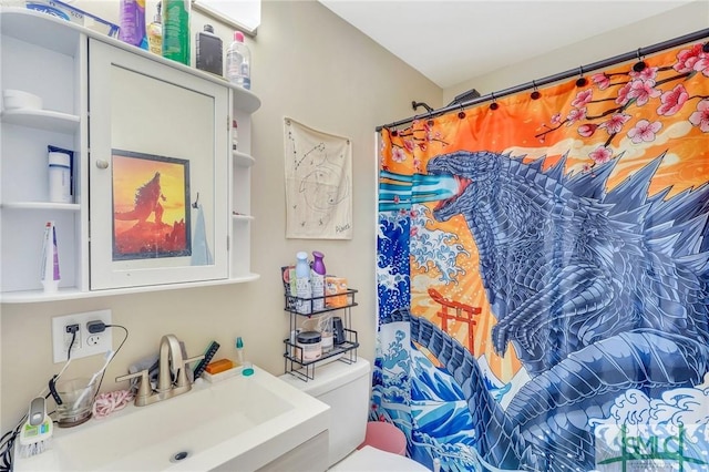 bathroom featuring a shower with shower curtain, toilet, and sink