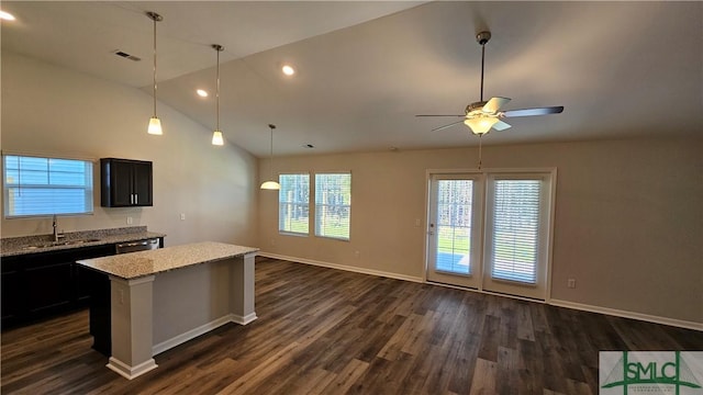 kitchen featuring ceiling fan, sink, dark wood-type flooring, light stone counters, and vaulted ceiling