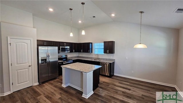 kitchen featuring light stone countertops, high vaulted ceiling, pendant lighting, a kitchen island, and appliances with stainless steel finishes