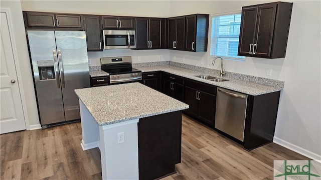 kitchen featuring appliances with stainless steel finishes, light wood-type flooring, dark brown cabinets, sink, and a kitchen island