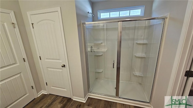 bathroom featuring wood-type flooring and a shower with shower door