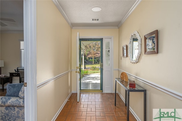 doorway with a textured ceiling, plenty of natural light, and crown molding