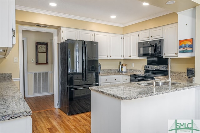 kitchen with black appliances, white cabinets, crown molding, light stone countertops, and kitchen peninsula