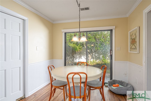 dining space with hardwood / wood-style floors, ornamental molding, and a chandelier