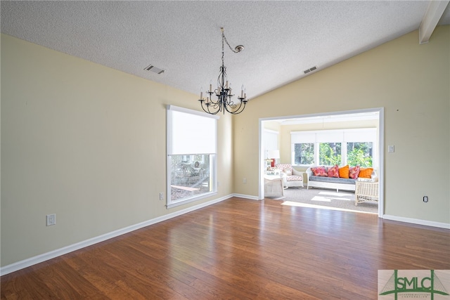 unfurnished dining area featuring vaulted ceiling with beams, wood-type flooring, a textured ceiling, and an inviting chandelier