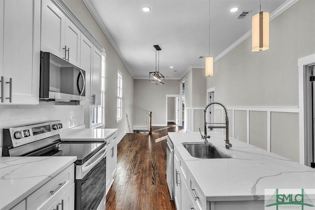 kitchen featuring stainless steel appliances, a kitchen island with sink, sink, decorative light fixtures, and white cabinets